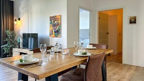 Un comedor con una mesa de madera dispuesta para cuatro personas, rodeada de sillas tapizadas en tonos marrones.