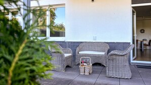 Un patio cubierto con muebles de mimbre y una cesta de mimbre con botellas.