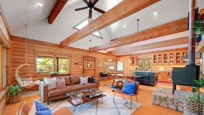 Een ruim interieur van een houten chalet met een zithoek, eethoek en keuken.