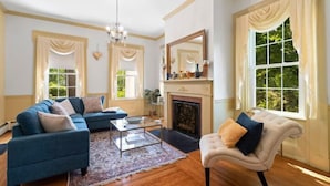 A living room with a fireplace, a sofa, a chair, and large windows.
