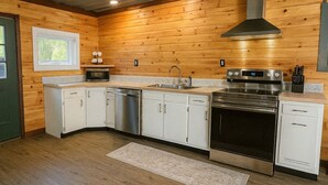 Una cocina moderna con armarios blancos, electrodomésticos de acero inoxidable y techo de madera.