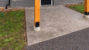 Una cabaña con un porche cubierto, una puerta negra y el número 145 en el poste.