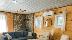 Una sala de estar acogedora con pared de piedra, chimenea, sofá, mesa de centro y dos sillones.