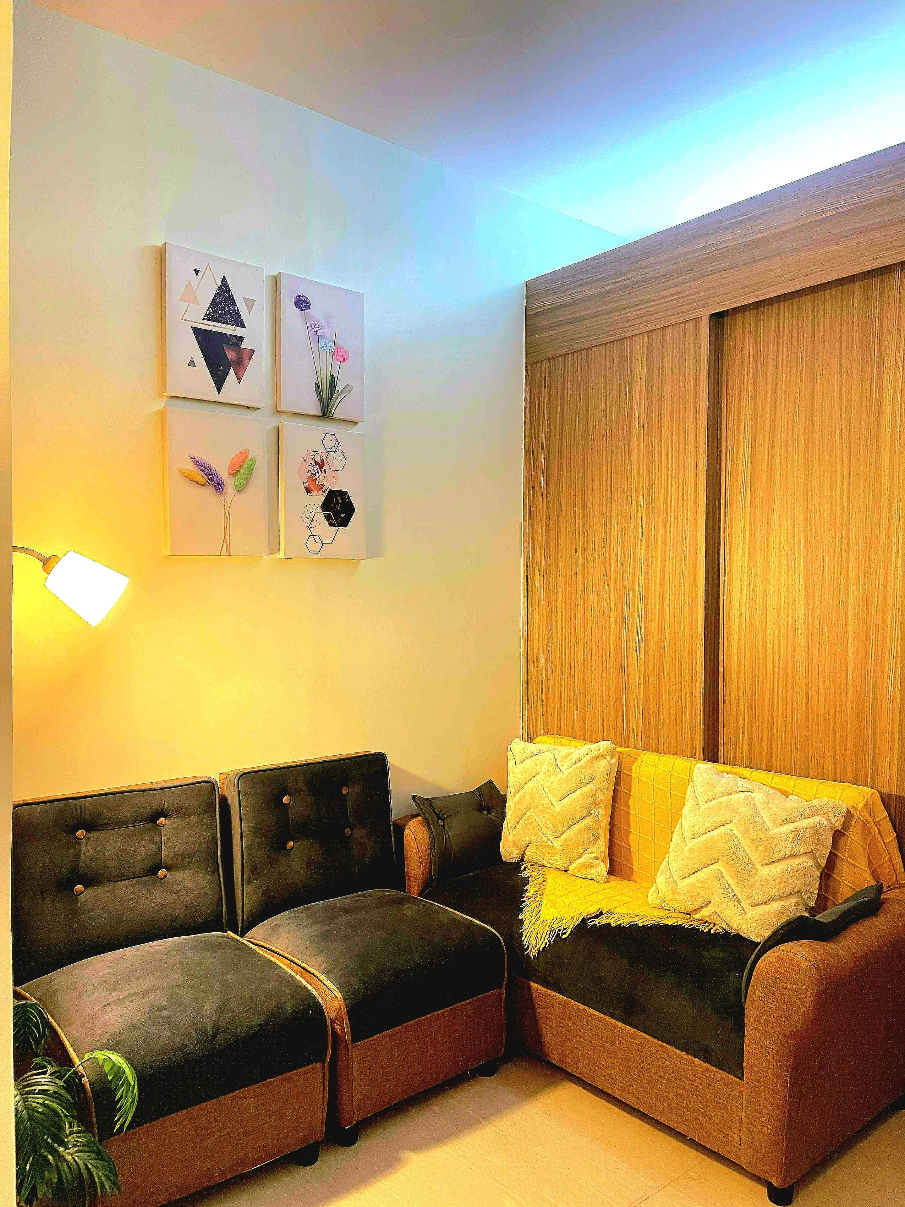 A living room with a sectional sofa, a lamp, and wall art.