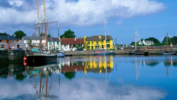 A harbor with boats, a yellow building, and a calm blue sky.