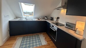 A compact kitchen with a window, a microwave, a stove, and a sink.