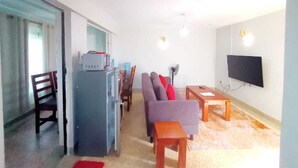 Ein Wohnzimmer mit einer Couch, einem Esstisch und einem Fernseher.
