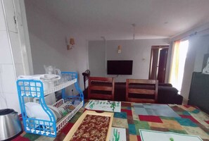 A room with a dining table, chairs, a TV, and a window with curtains. - Lux Suites Musundi Homes Kakamega (Kakamega)