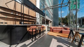 Eine moderne Bar mit einer Holztheke, mehreren Hockern und einer Sitzecke mit Sofa.