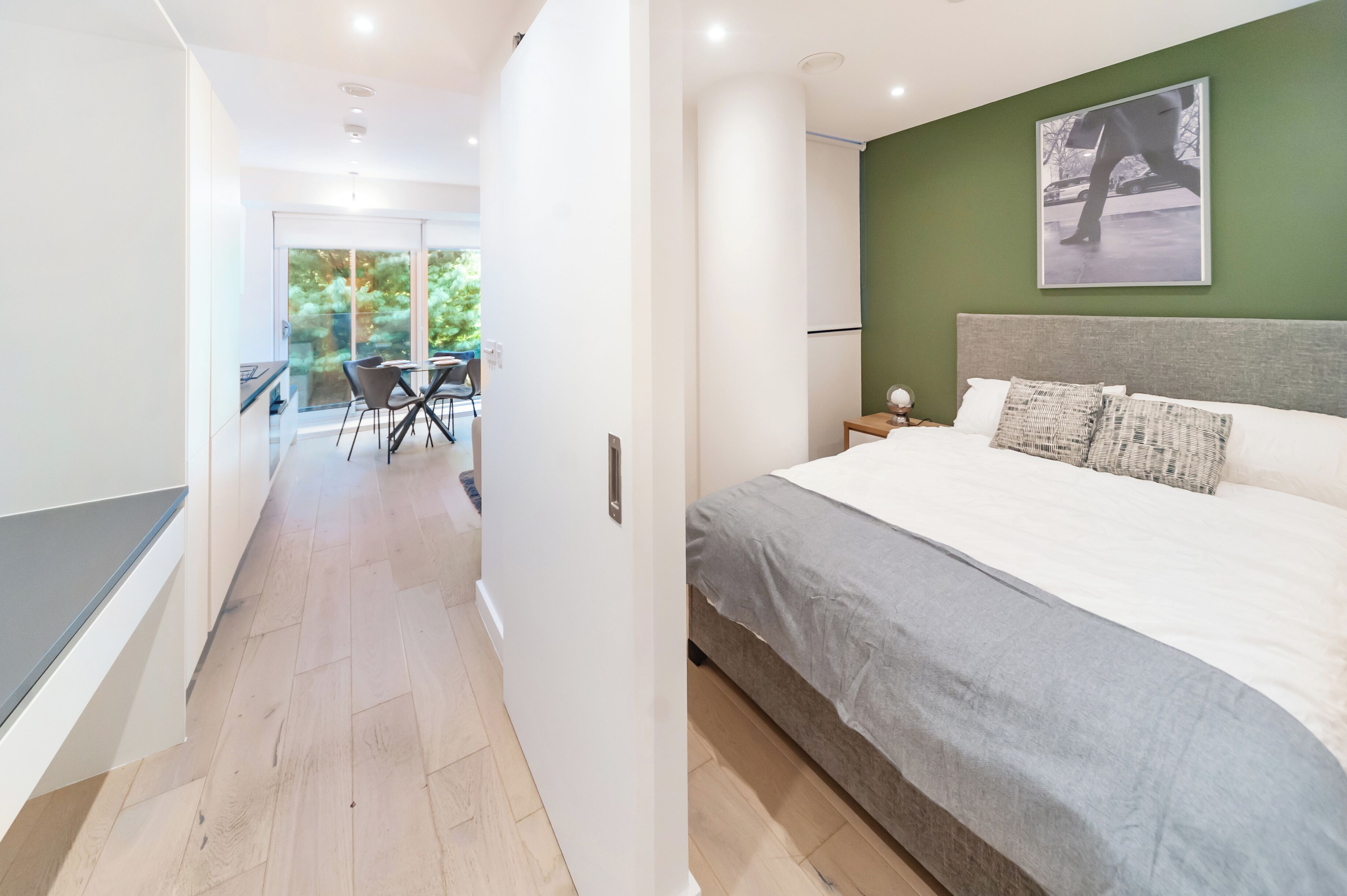 Una camera da letto moderna con un letto grande, una parete verde decorativa e vista sull'esterno.