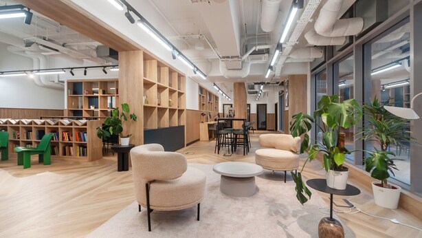 Un espace de bureau moderne, doté d'étagères en bois, de sièges confortables et de plantes en pot.