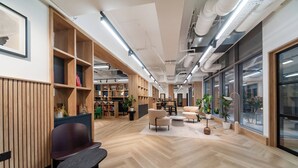 Un intérieur moderne avec des étagères en bois, un parquet en point de Hongrie et de grandes fenêtres.