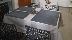 En matplats med ett bord dukat för fyra personer, en träskommod, en spegel och konst på väggen.