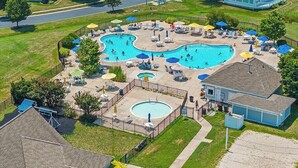 Un quartier résidentiel doté d’une grande piscine circulaire, entourée de chaises longues et de parasols.