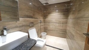 A modern bathroom with a marble wall, a white sink, and a toilet. - Hotel Scarlet (Gwalior)