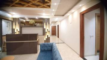 A modern reception area with a reception desk, a blue sofa, and a hallway leading to a door.