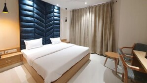 A modern bedroom with a large bed, a desk, and a chair. - Hotel Scarlet (Gwalior)