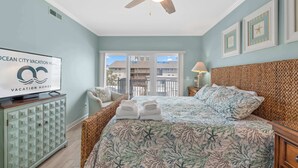 Une chambre à coucher avec un lit, une télévision, un ventilateur de plafond et une vue sur l’extérieur.