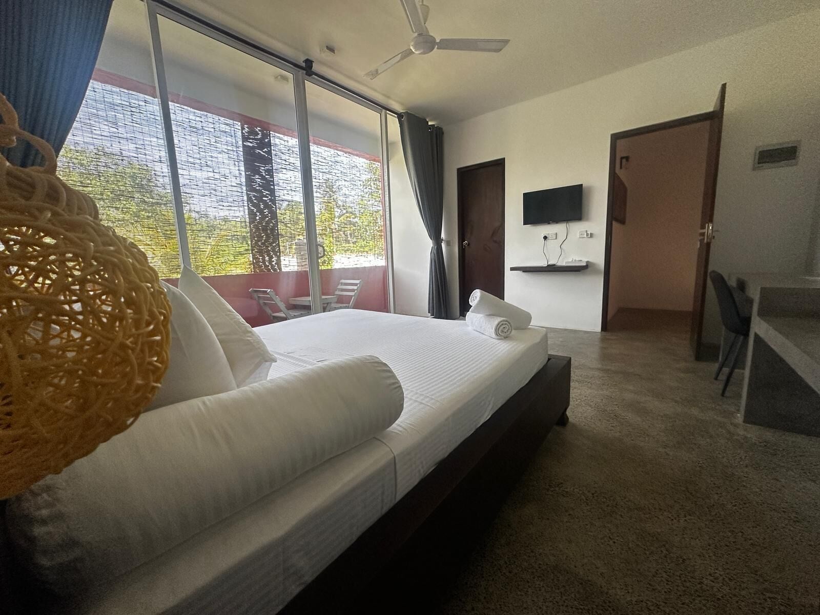 A hotel room with a bed, a TV, a desk, and a balcony with a view.