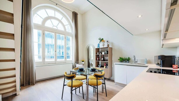 Eine moderne Küche mit Essbereich, ausgestattet mit einem großen Fenster, einer eingebauten Bücherablage und einer Kücheninsel.