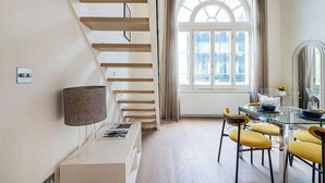 Ein modernes Interieur mit einer Treppe, einem Essbereich mit gelben Stühlen und einem großen Bogenfenster.