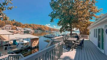 A wooden deck with outdoor seating overlooking a marina with docked boats.