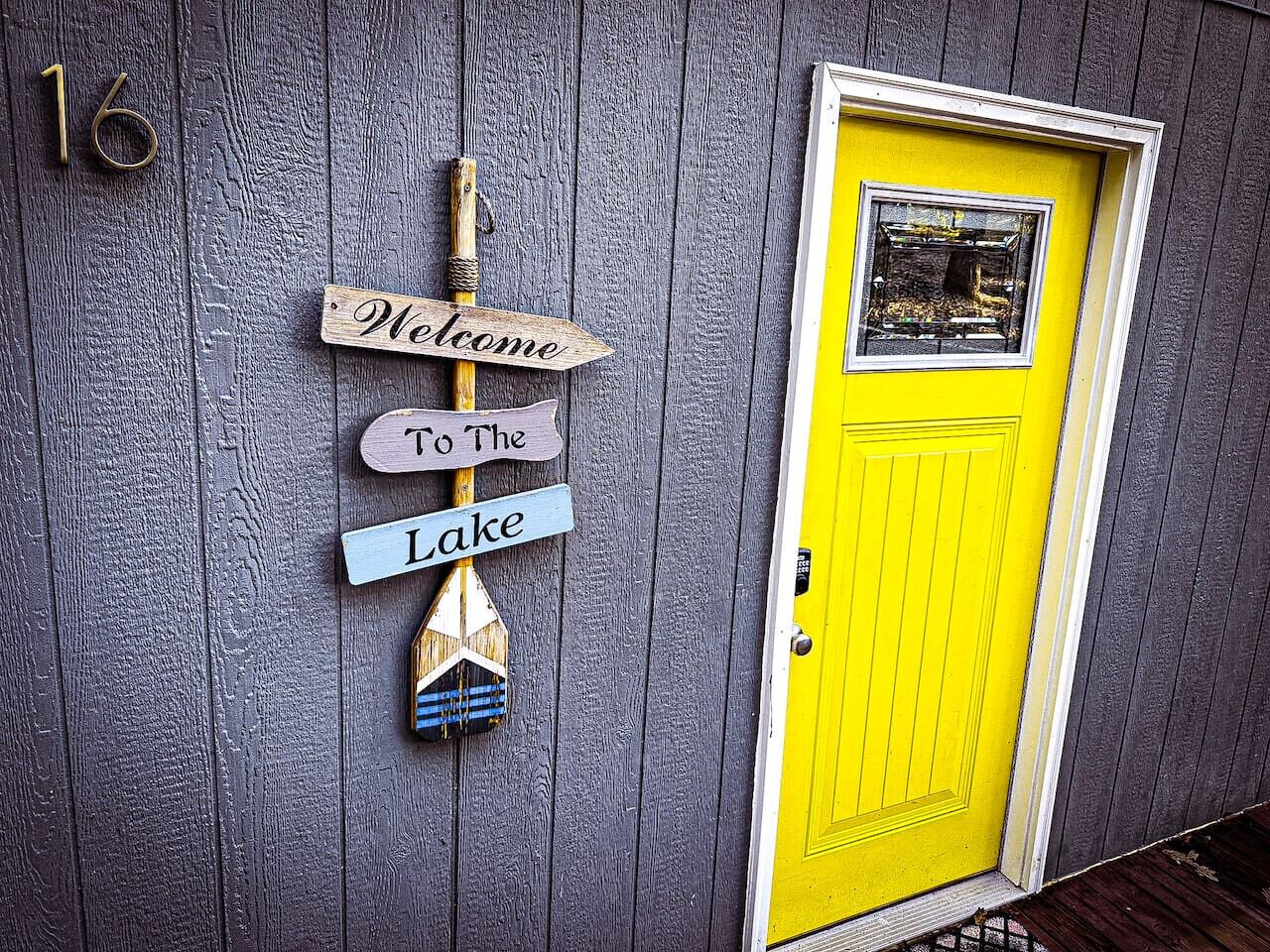 A wooden sign with 'Welcome to The Lake' and a blue and white boat.