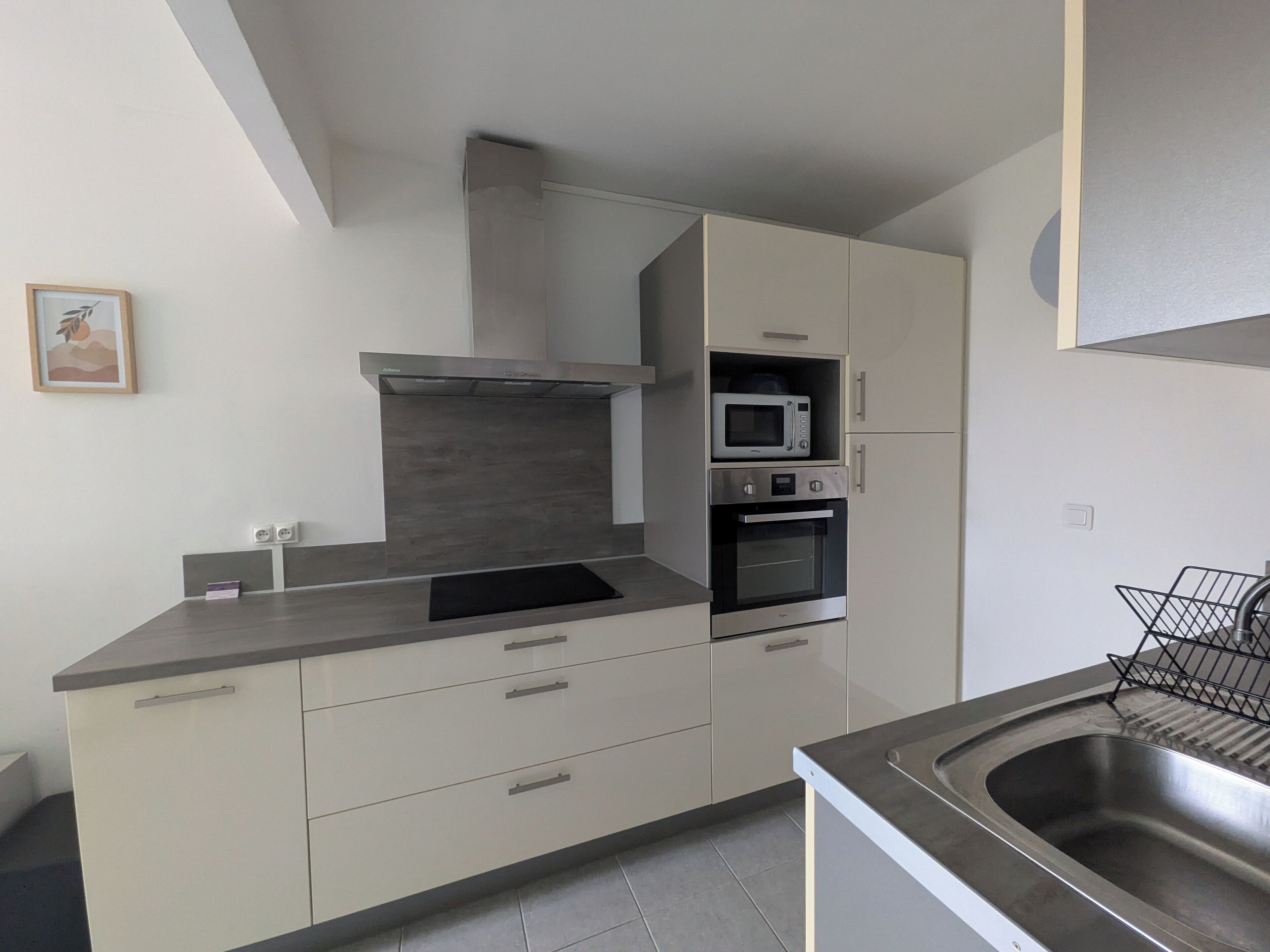 A modern kitchen with a built-in microwave, oven, and stainless steel sink.