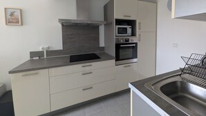 Eine moderne Küche mit integriertem Mikrowellenherd, Backofen und Spüle aus Edelstahl.