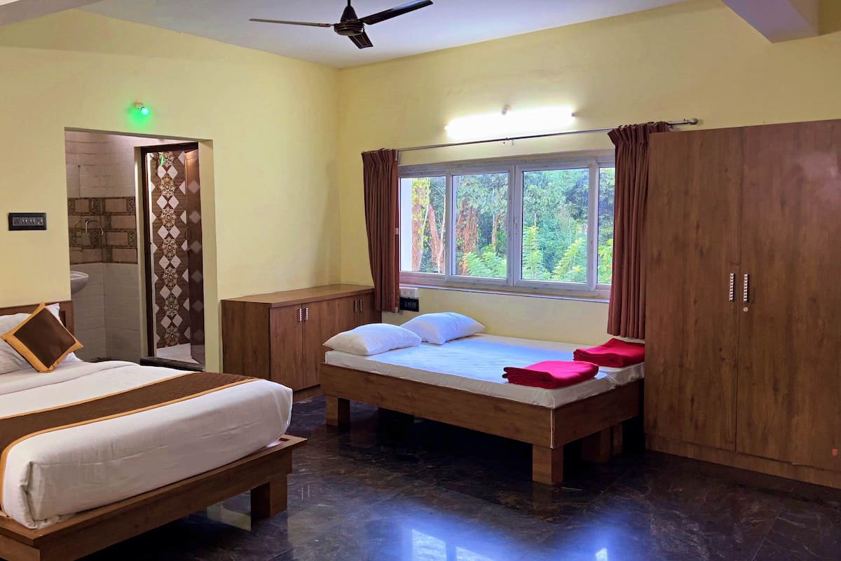 Una habitación de hotel con dos camas, una ventana con cortinas, un armario de madera y un ventilador de techo.