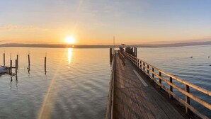 A wooden pier extending into calm water with a sunset in the background. - Charming Apartment with Private Access at Thoeny (Utting am Ammersee)