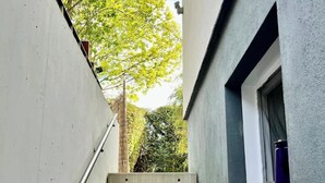 A narrow concrete staircase with metal handrails, leading to a window with a view of trees and a clear sky. - Charming Apartment with Private Access at Thoeny (Utting am Ammersee)