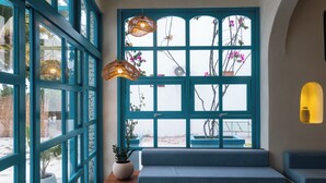 A room with a large window, a bench, and a potted plant. - Endorphins Beach Villa (Dhiffushi)