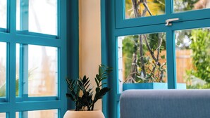 A room with large windows, a wicker lamp, a potted plant, and a blue sofa. - Endorphins Beach Villa (Dhiffushi)