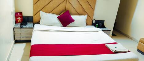 A neatly made bed with a wooden headboard, white bedding, and a red throw blanket.
