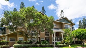 Un edificio residenziale a più piani con un balcone a due livelli al secondo piano, immerso in prati curati e alberi.