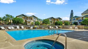 Una piscina con lettini prendisole e una vasca idromassaggio, circondata da palazzi.