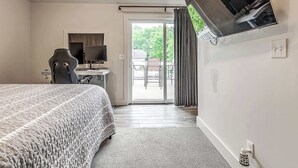 Een slaapkamer met een bed, een bureau met een computer en een televisie.