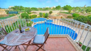 Uma varanda com piscina, uma mesa com cadeiras e vista para a paisagem ao redor.