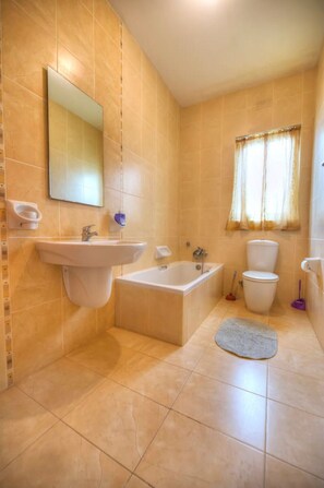 Ein Badezimmer mit Waschbecken, Badewanne, Toilette und einem Fenster mit Vorhängen.