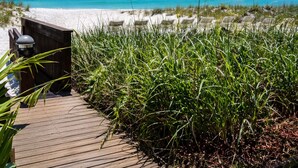 A wooden pathway leading to beach chairs on a sandy shore, with a clear blue sky above. - Renovated 2 Bed, 2 Bath, Beachfront w/ Gulf views (Longboat Key)