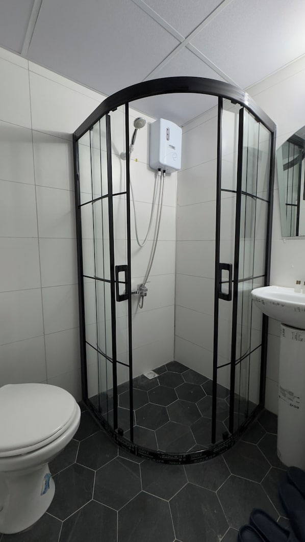 A bathroom with a glass-enclosed shower, a toilet, and a sink. - TERAS GARDEN BUNGALOV HATAY (Altınözü)