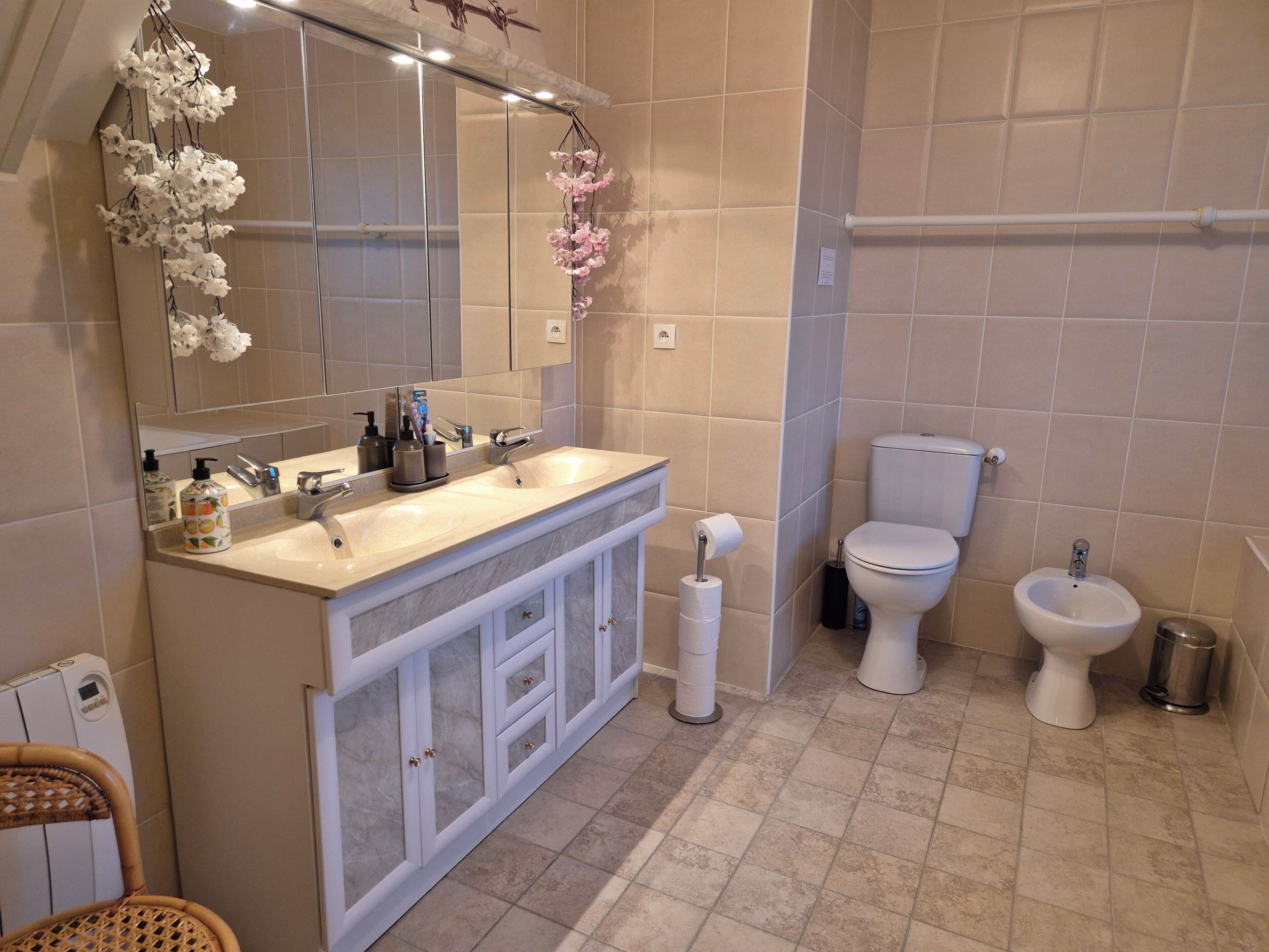 A modern bathroom with a large mirror, two sinks, a toilet, and a bidet.