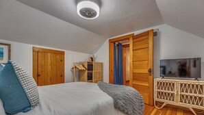 A bedroom with a bed, wooden wardrobe, TV stand, and a ceiling fan. - Fresh Coast Craftsman - Pet Friendly | Near Lake (Sheboygan)