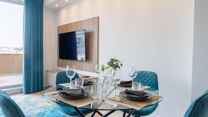 A modern dining area with a glass table, blue upholstered chairs, and a city view. - Top Location Penthouse in St. Julian's - 4 Guests (Saint Julian's)