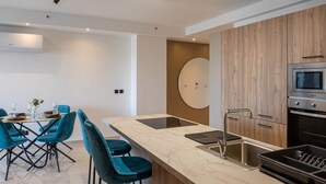 Een moderne keuken met een marmeren aanrechtblad, een inbouwoven en een eethoek met teal stoelen.