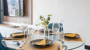 Een eettafel gedekt met borden, bestek, glazen en een vaas met bloemen.