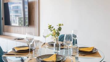 A dining table set with plates, cutlery, glasses, and a vase with flowers.