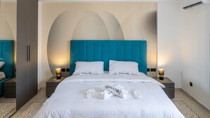 Hotelkamer met een groot bed, twee nachtkastjes met lampen, een kledingkast en een wand met een geometrisch ontwerp.