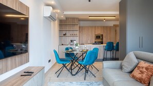Een moderne keuken met houten kastjes, een eethoek met blauwe stoelen, en een grijze bank met kussen.